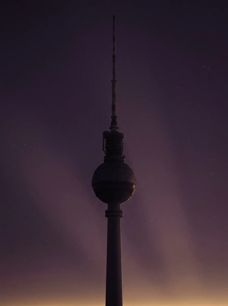 A dusk illustration of Berlin's Fernsehturm television tower against a plum sky